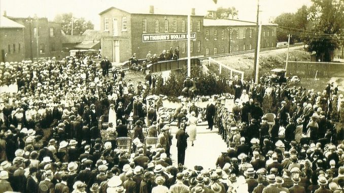Black and white photo shows a crowd around a cenotaph