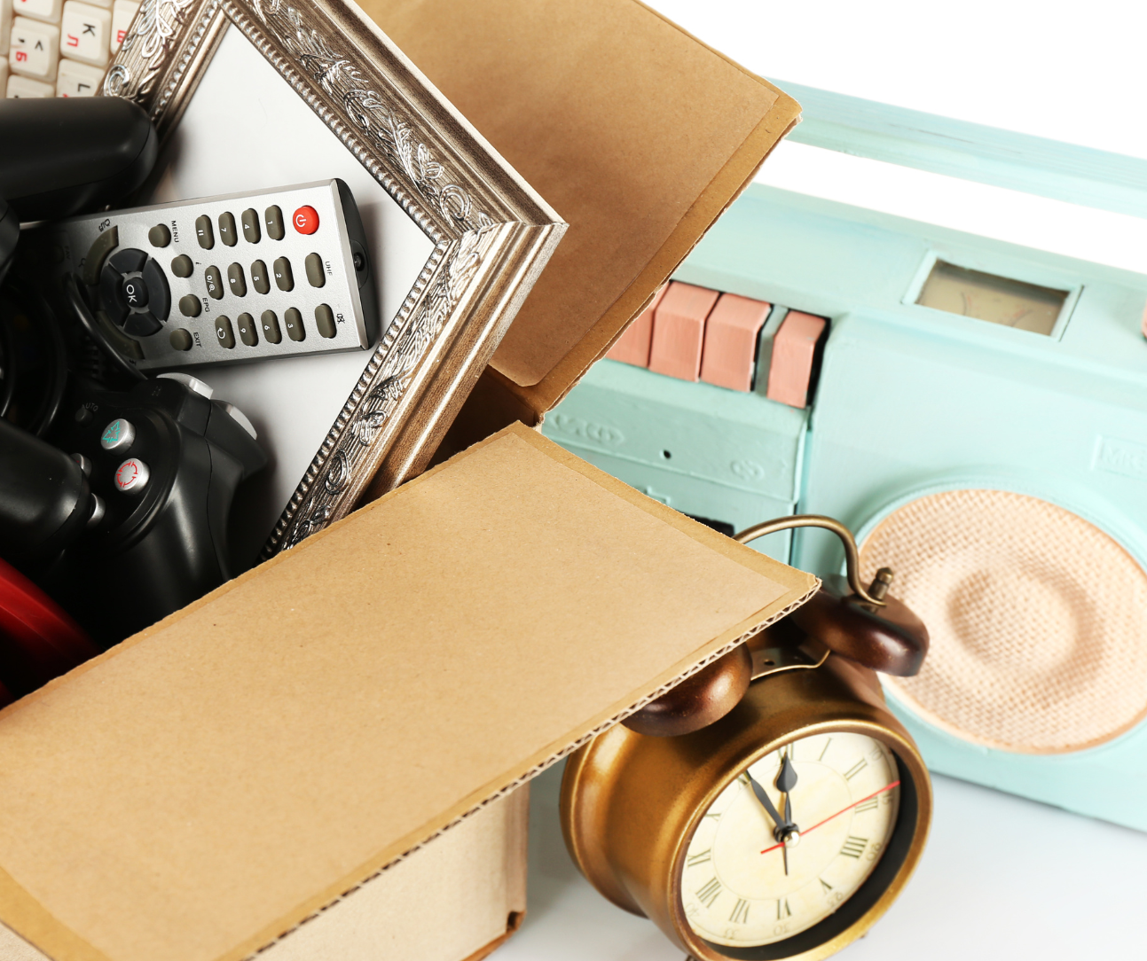 Cardboard box filled with TV remote, picture frame with a clock and radio sitting next to it