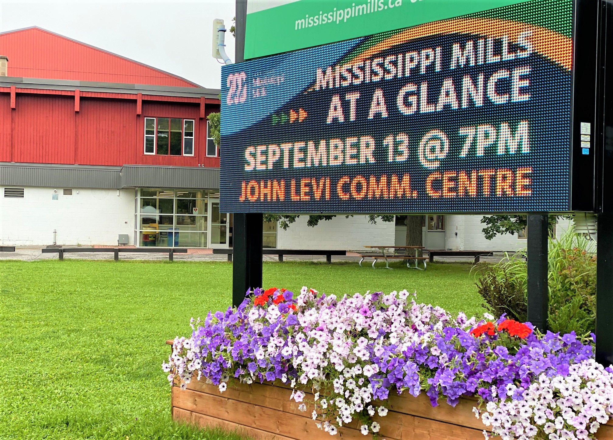 Digital sign reading 'Mississippi Mills at a Glance' in front of red and white building
