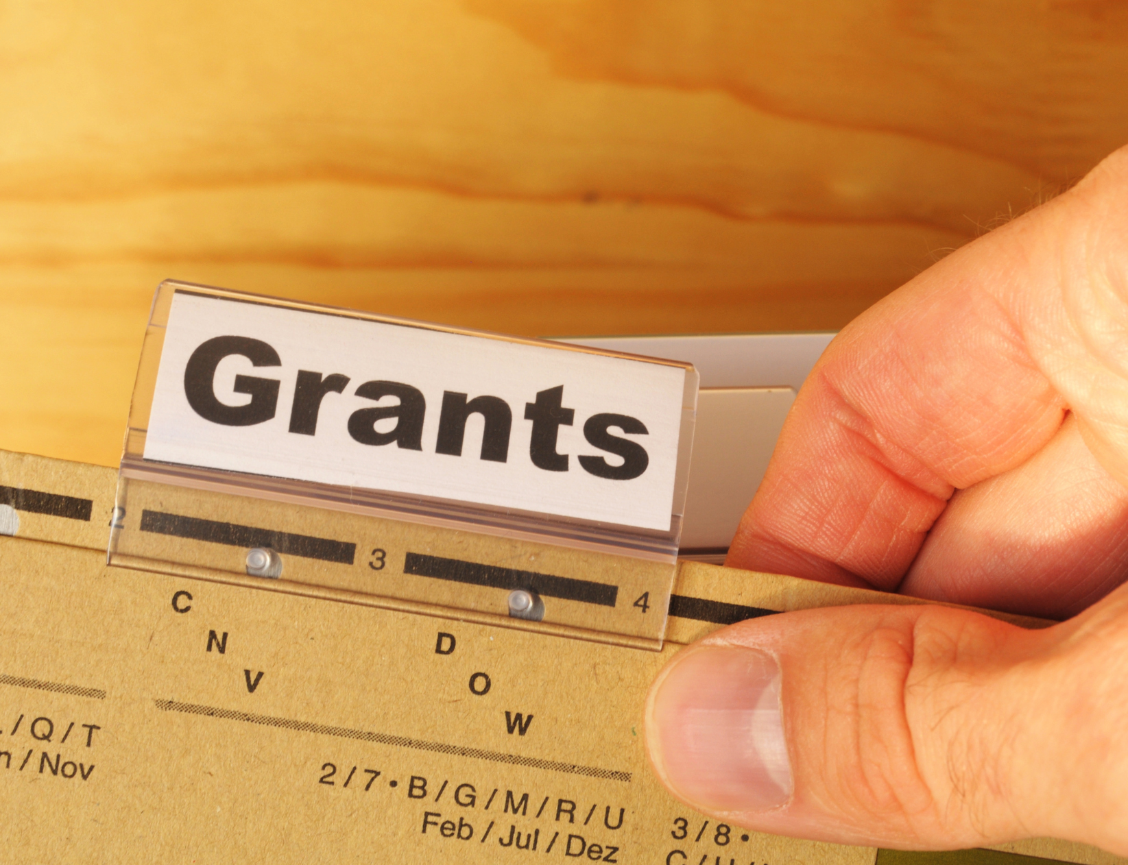 Hand holds folder entitled 'Grants'