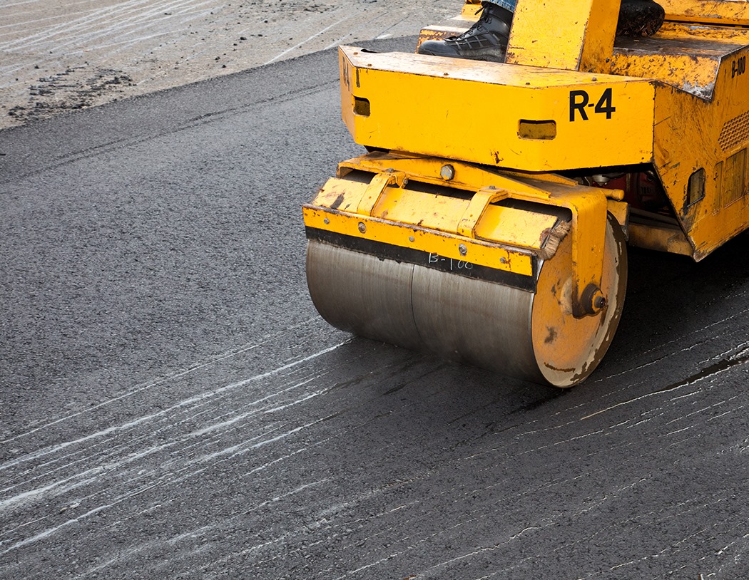 A yellow asphalt paving machine on a freshly paved road