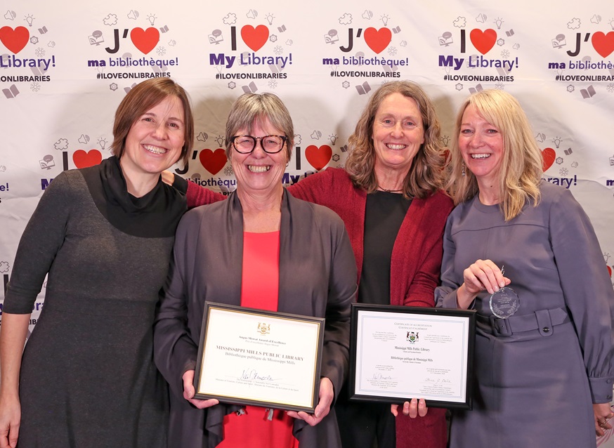 Four women stand with award against a white backdrop reading 'I Love My Library'