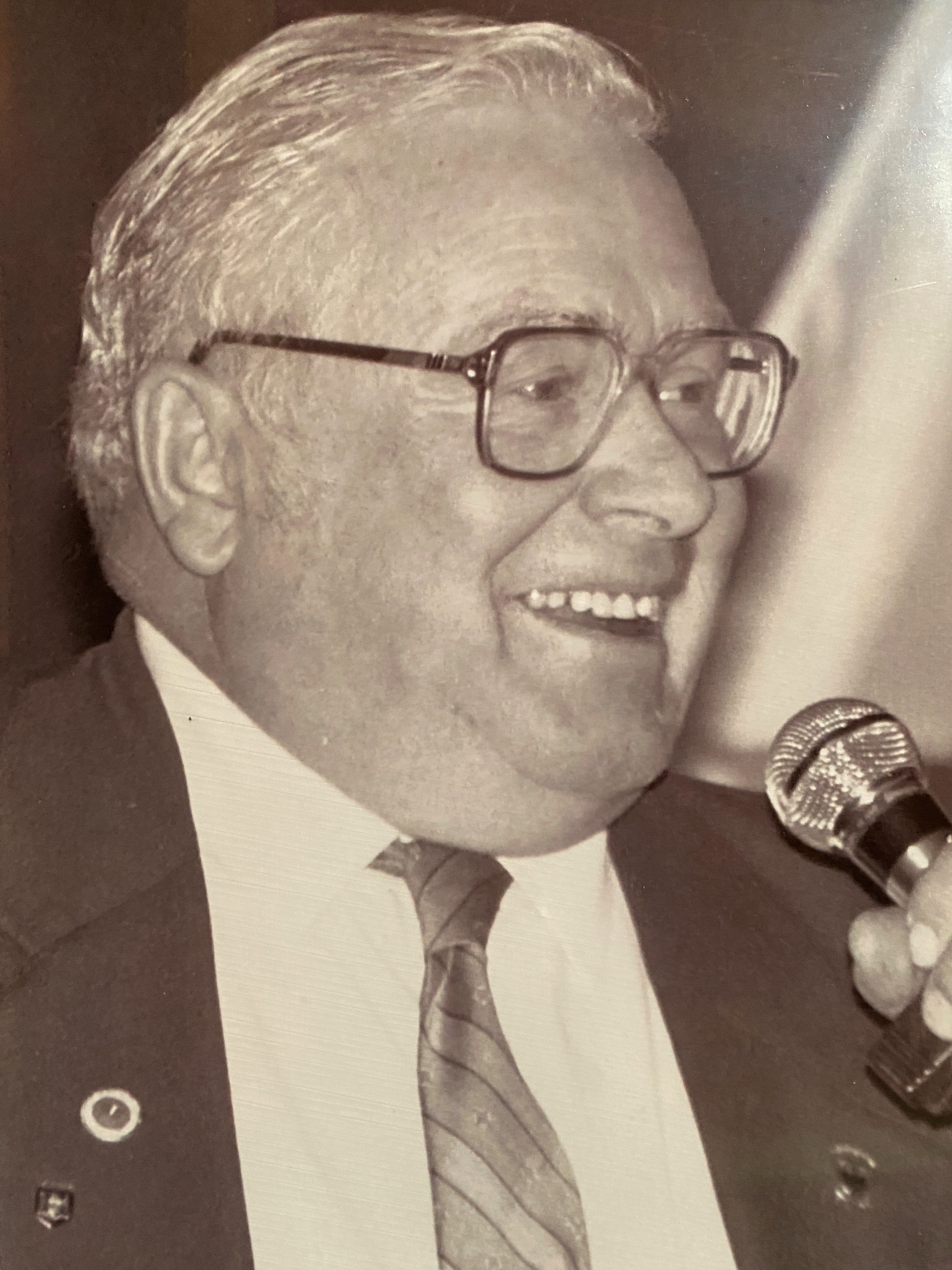 Black and white photograph of man in a business suit smiling and looking to the side