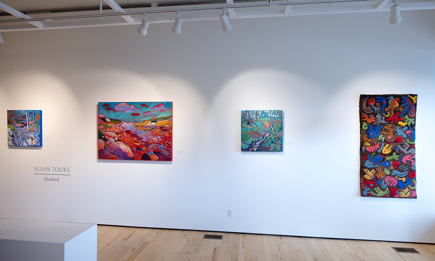 Photo of brightly coloured artwork hanging on a white gallery wall