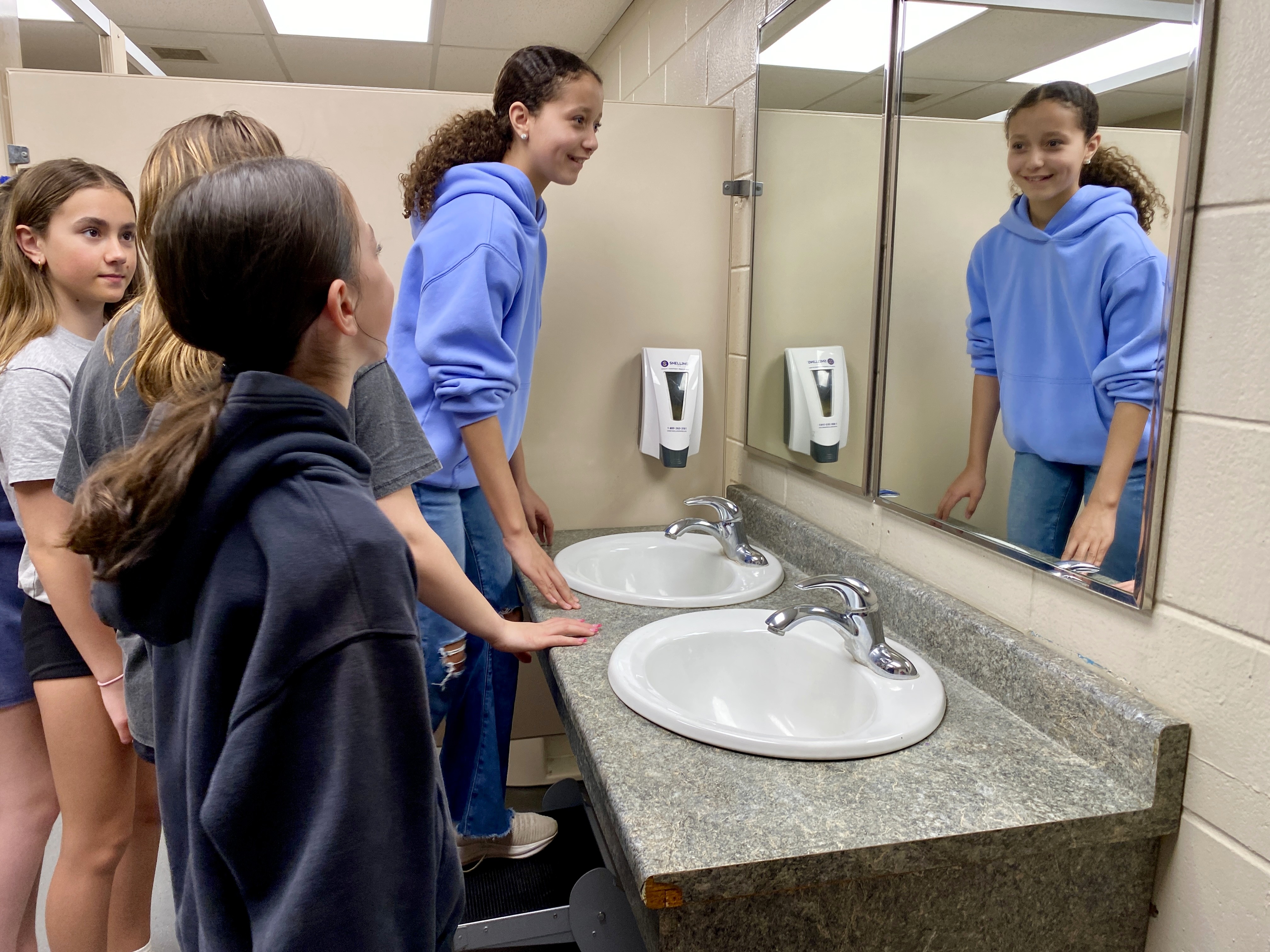 Students stand on Step 'n Wash unit in a public washroom