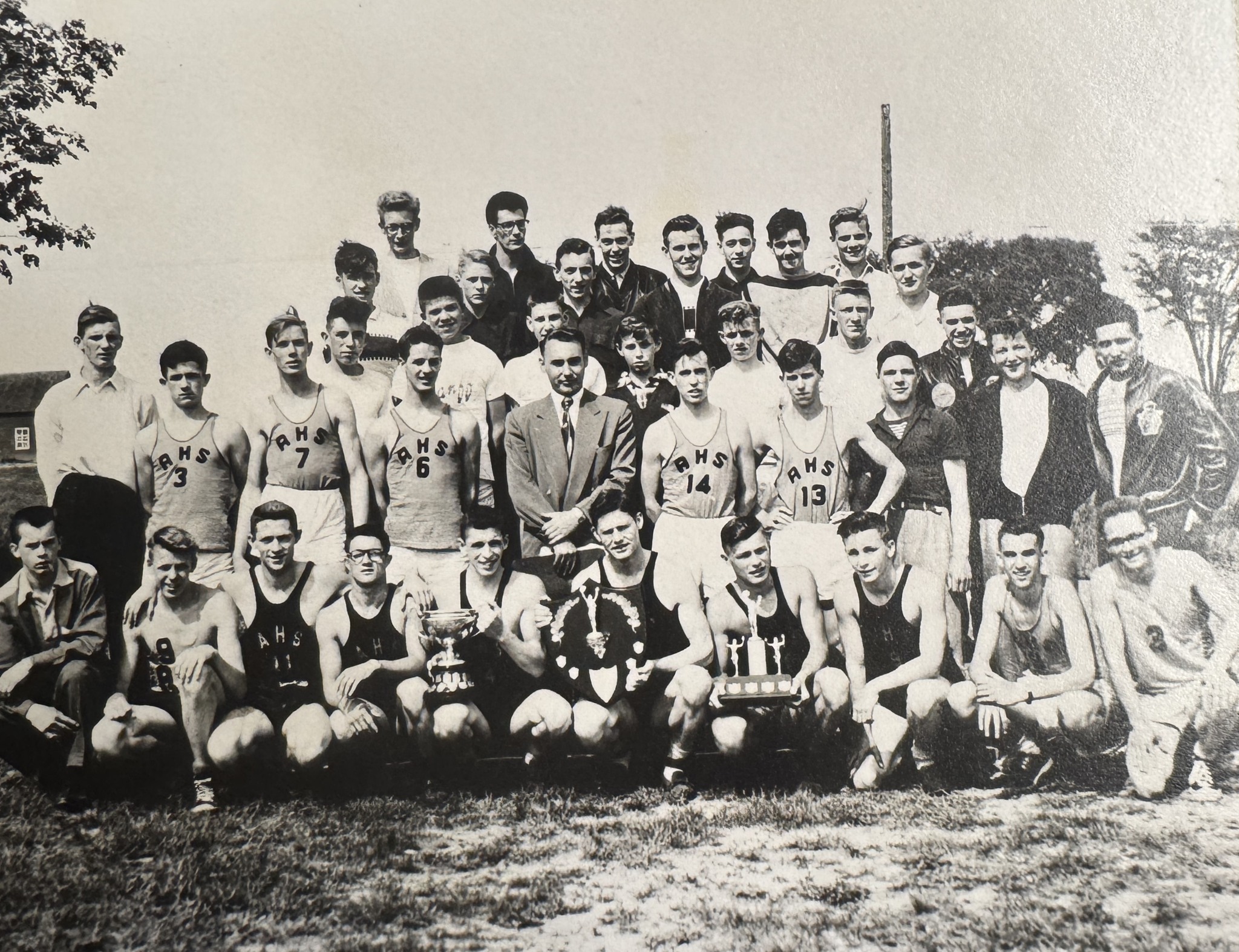 Black and white group photo of high school athletes with trophies