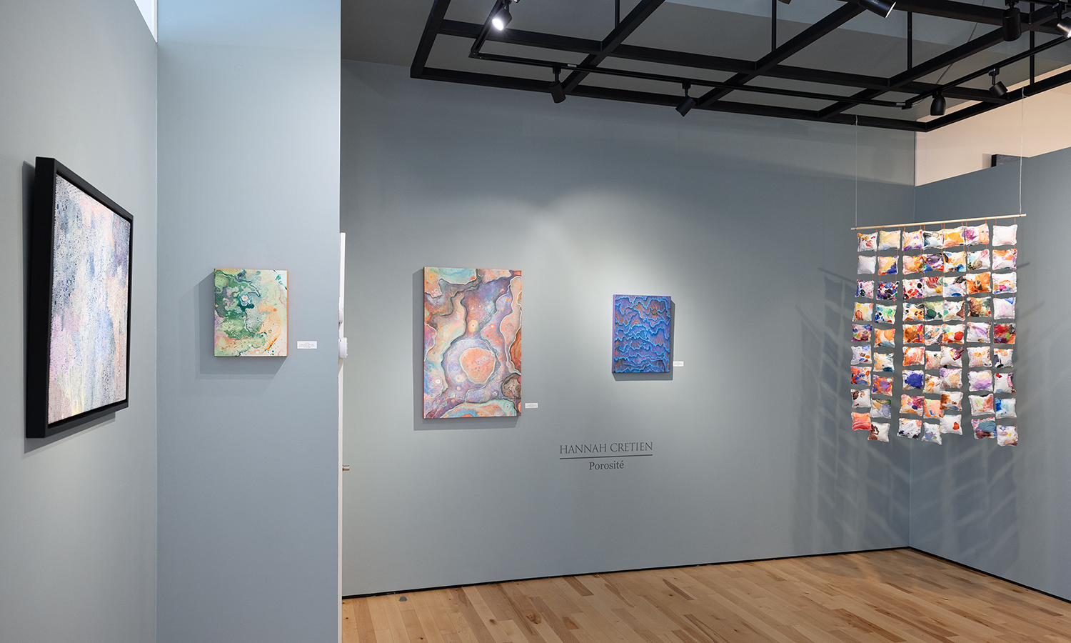 Photo of colourful artwork hanging on light grey gallery walls