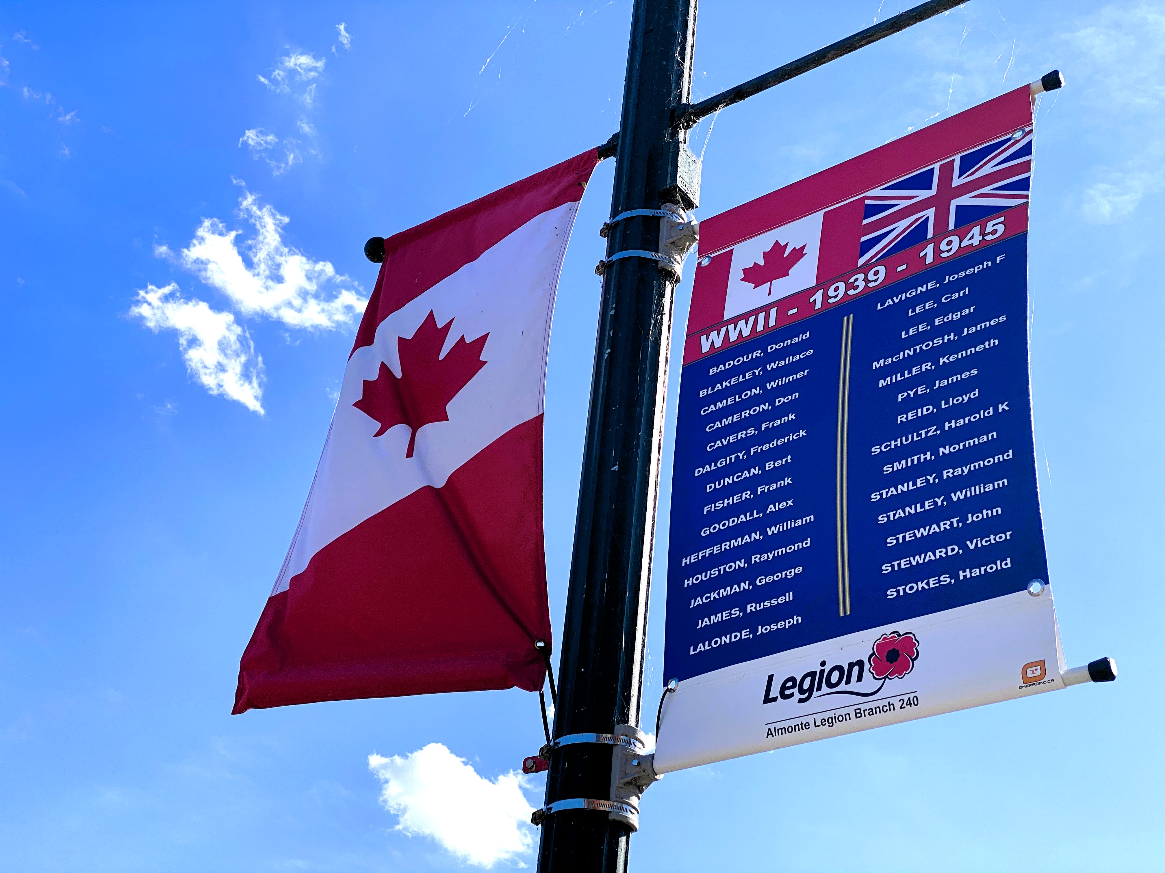 Close up of Canadian flag banner next to local a banner listing World War II veterans on a lamp post