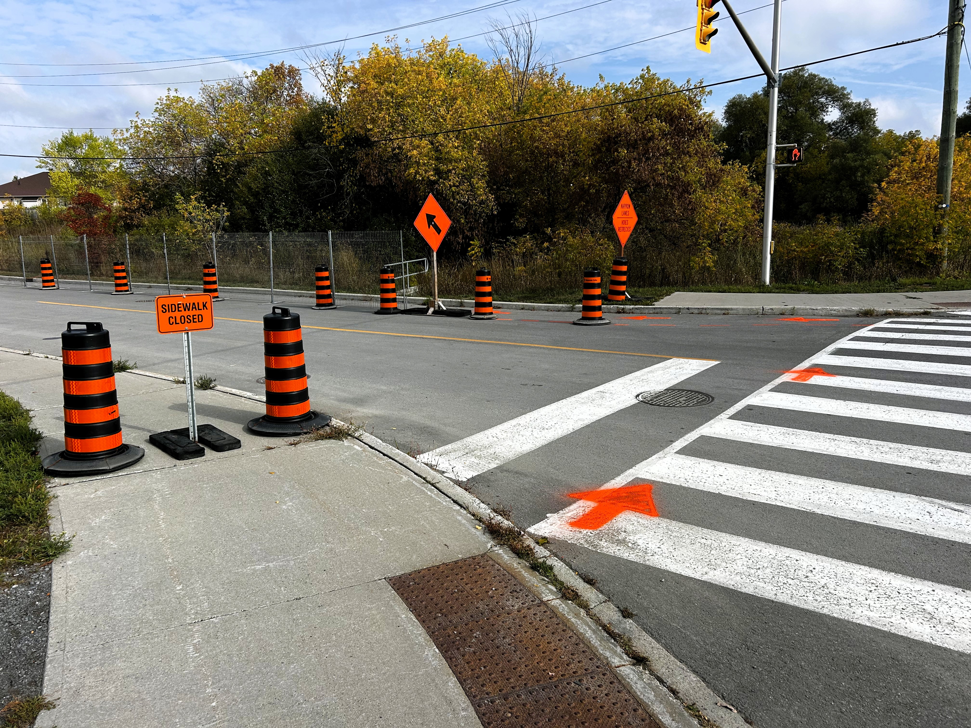 Photo showing crosswalk on street with sidewalk closed sign and directional signage