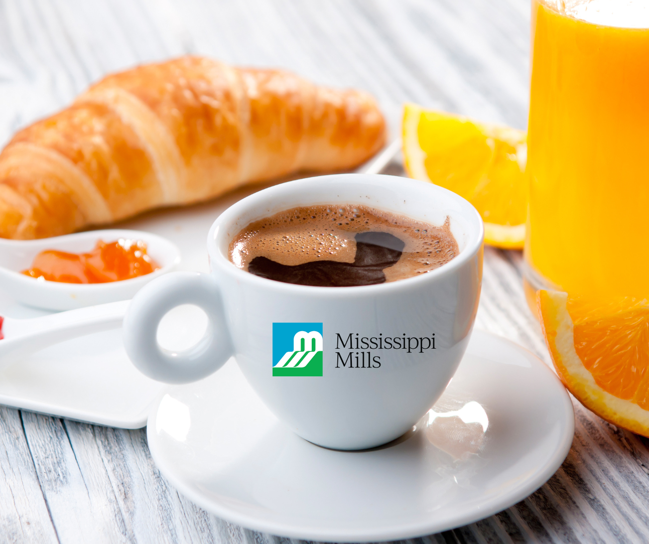 Photo of breakfast items on a table with a white coffee cup including the Mississippi Mills logo
