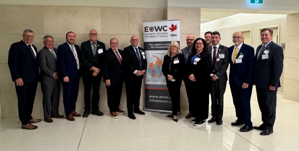 Photo of group of people standing in front of a banner in a hallway