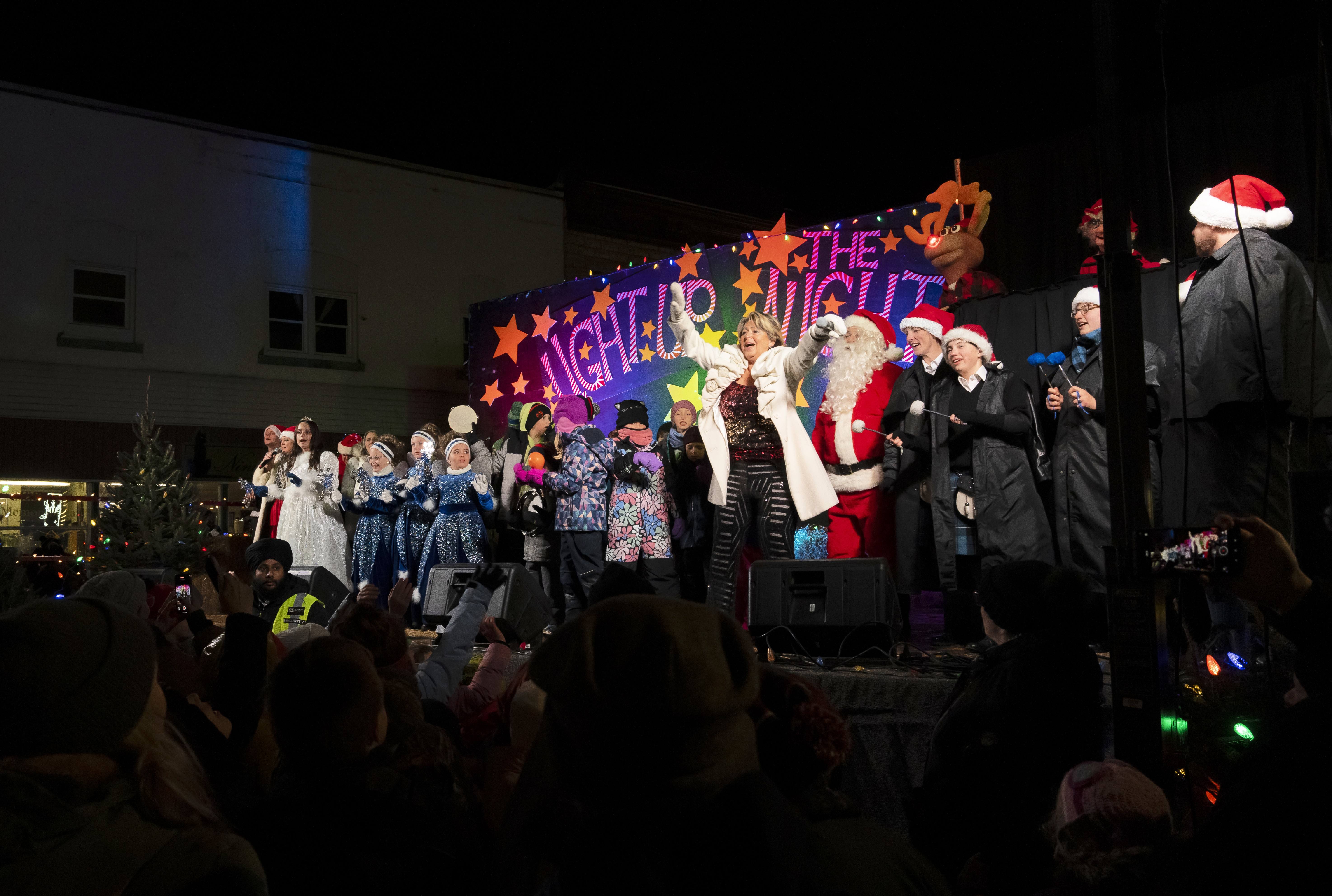 Photo of entertainers on a stage with a backdrop reading 'Light Up the Night'