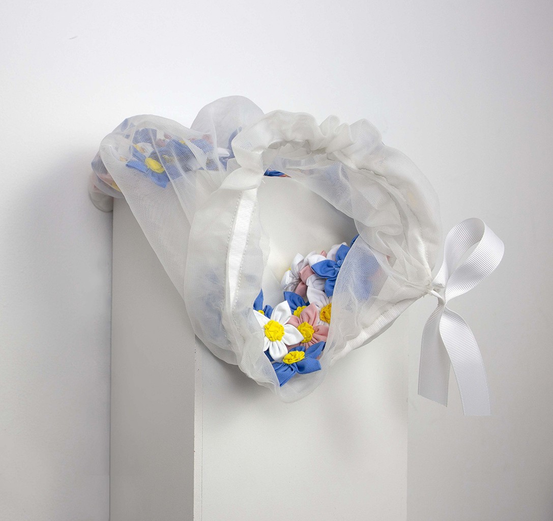 Art piece with brightly coloured flowers in a clear bag tied with a white satin ribbon