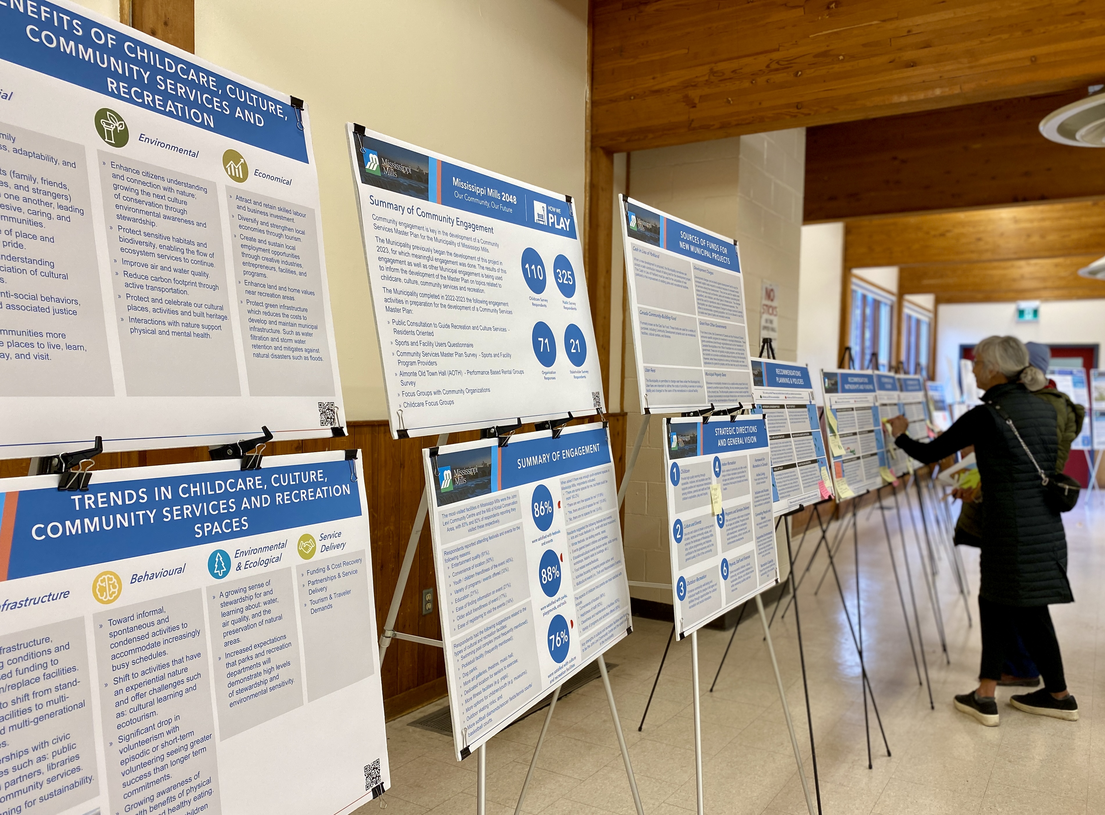 People read information boards sitting on easels