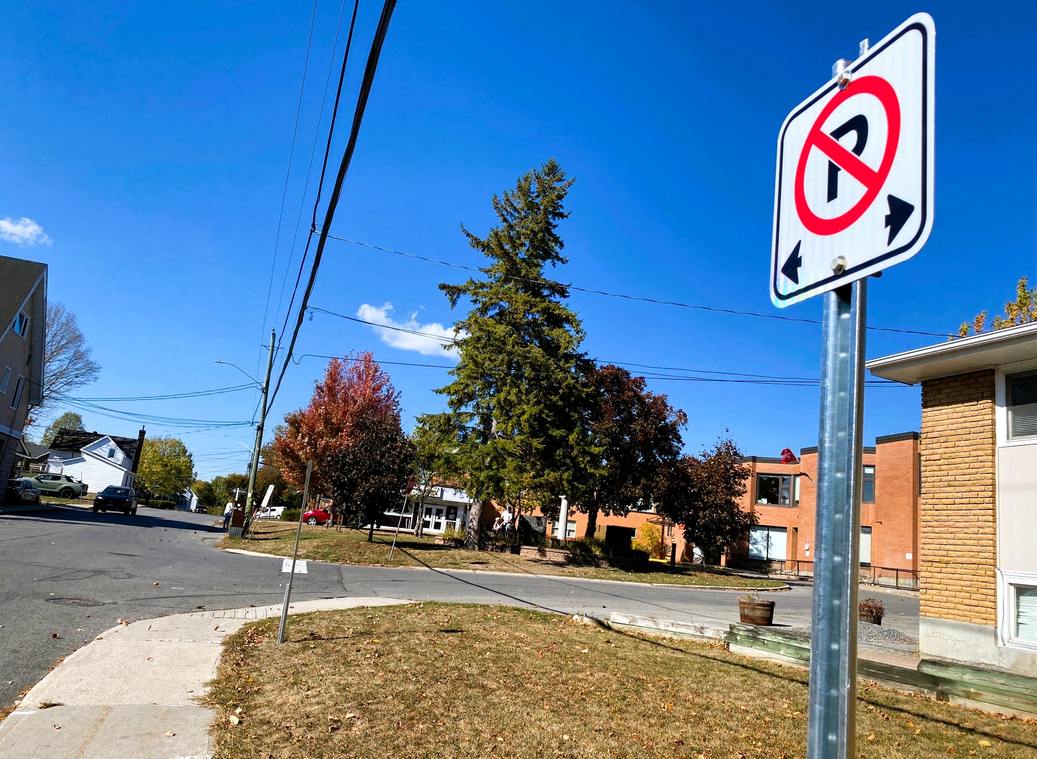 Photo of neighbourhood street with no parking sign in foreground and buildings in background