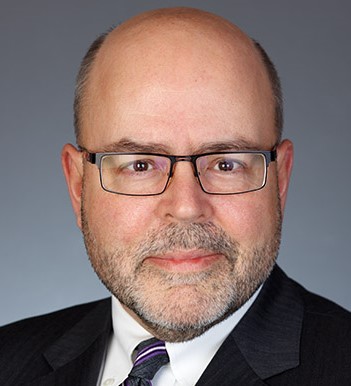Headshot of a bald man with glasses
