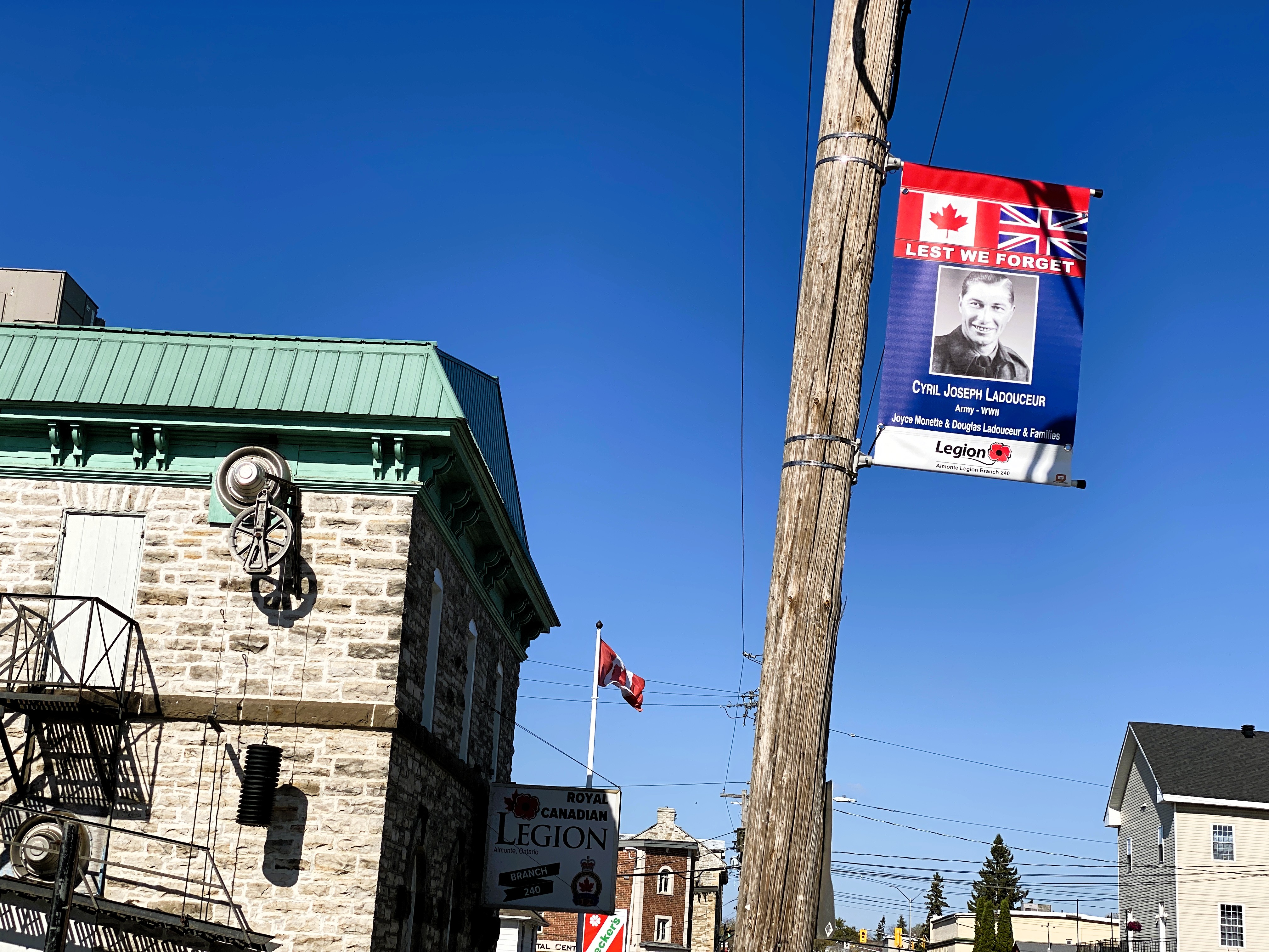 A red, white and blue banner honouring a veteran hangs from a telephone pole in front of the Almonte Legion
