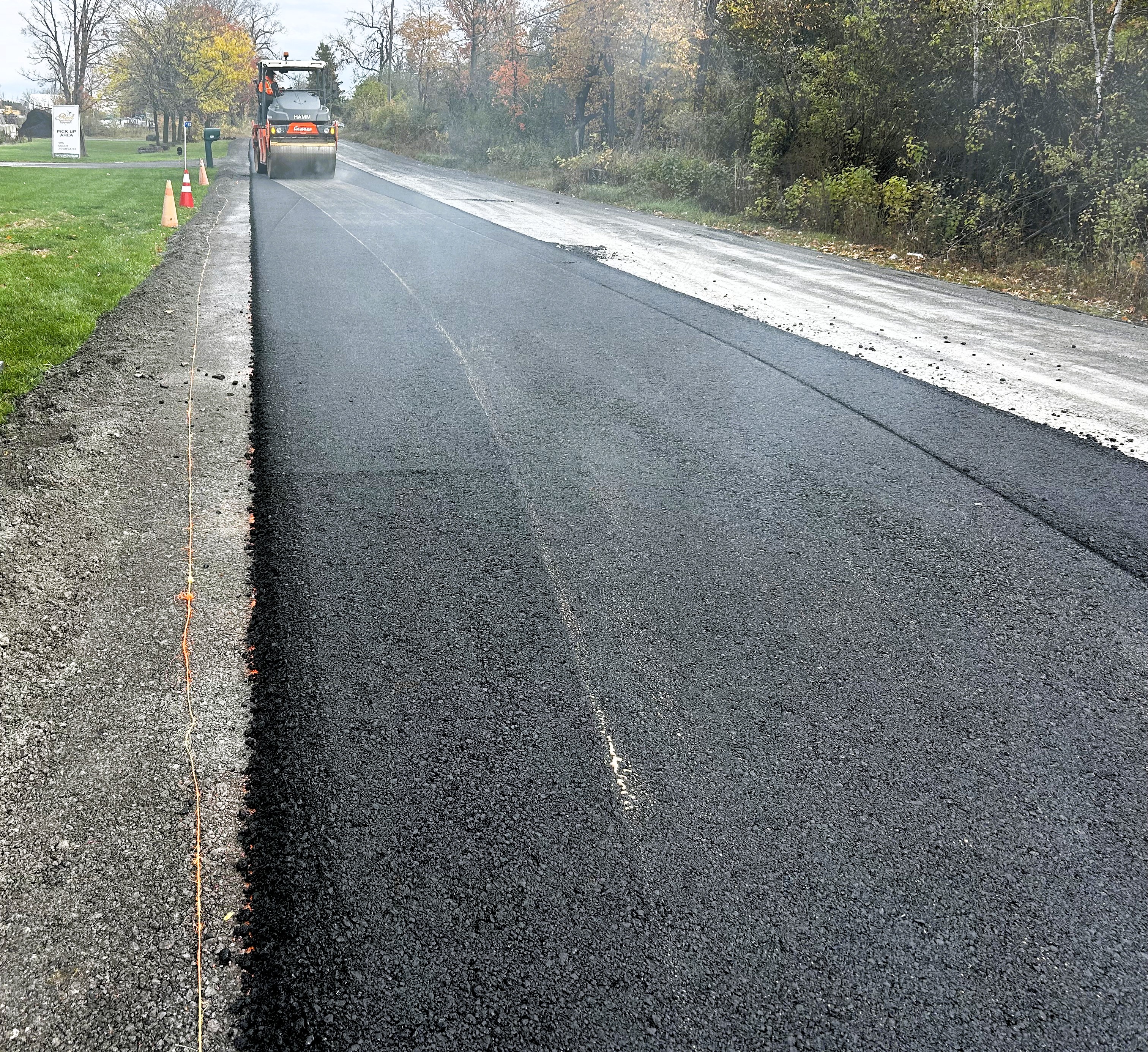 Paving equipment smooths asphalt on a rural road