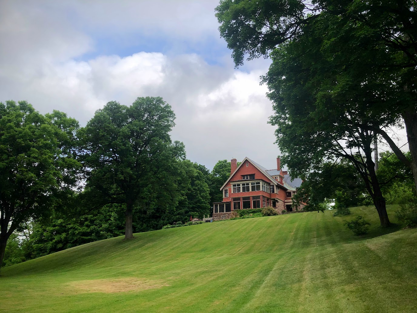 Photo of three-storey red home set back on a manicured lot