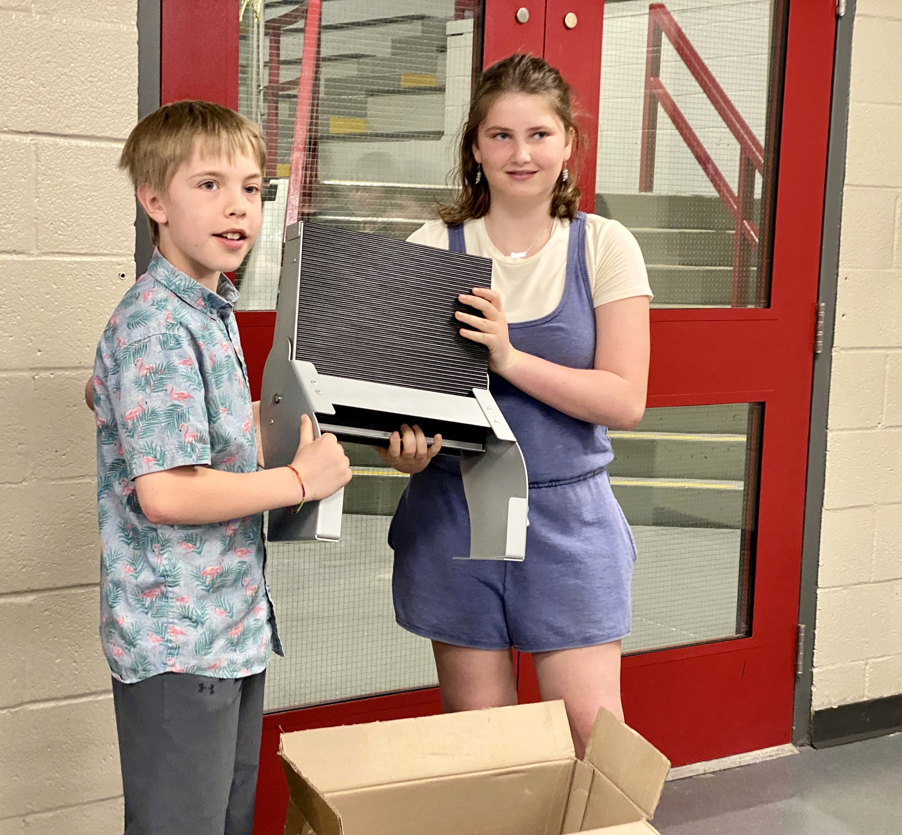 Two students hold up piece of equipment