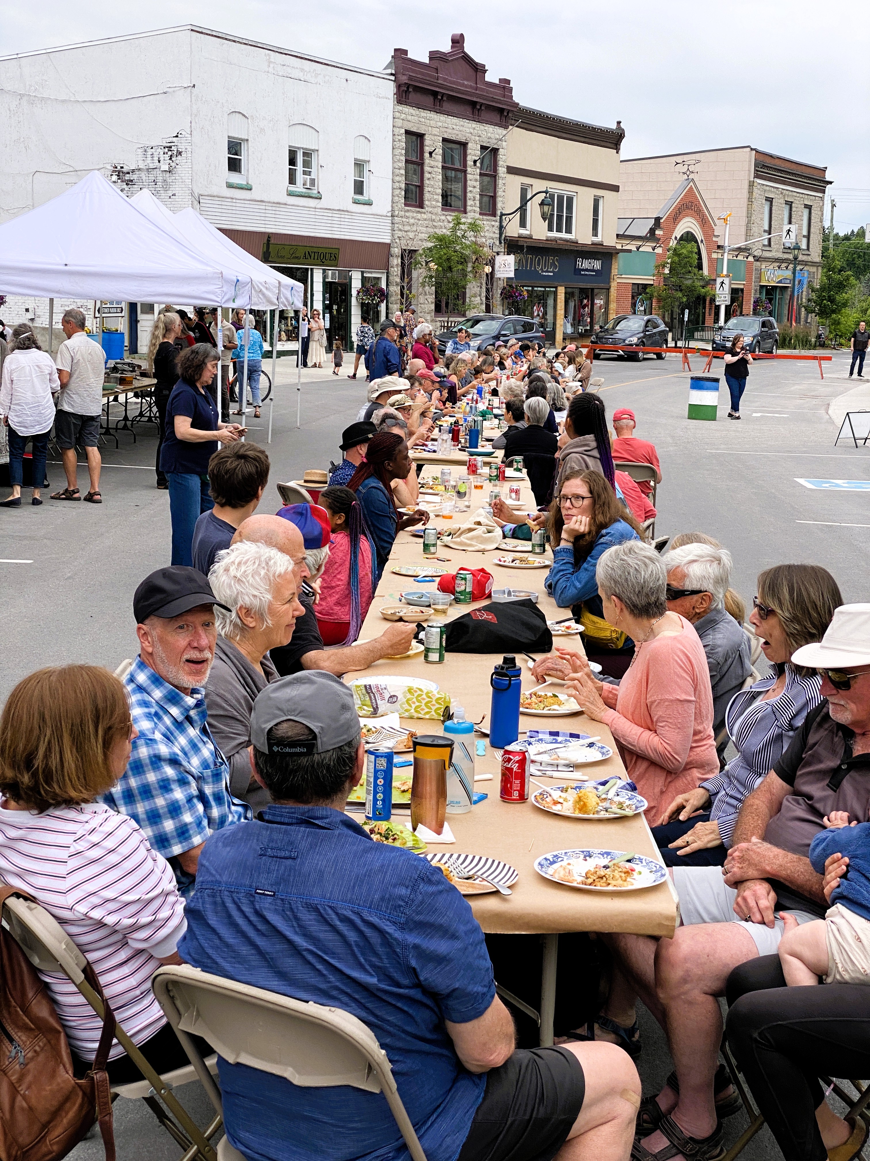 Dozens of people sit at long tables joined together in the middle of a downtown street