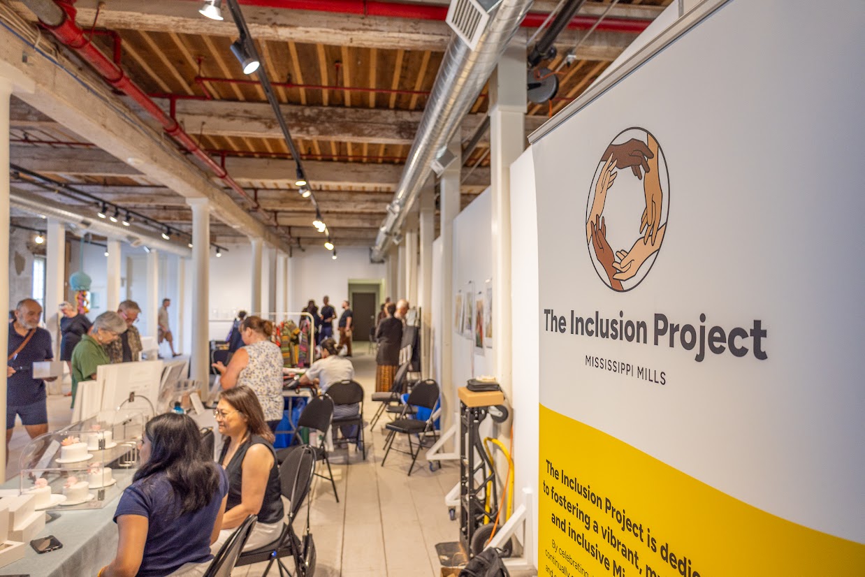 Vendors sitting at tables in a museum space with a banner poster in the foreground